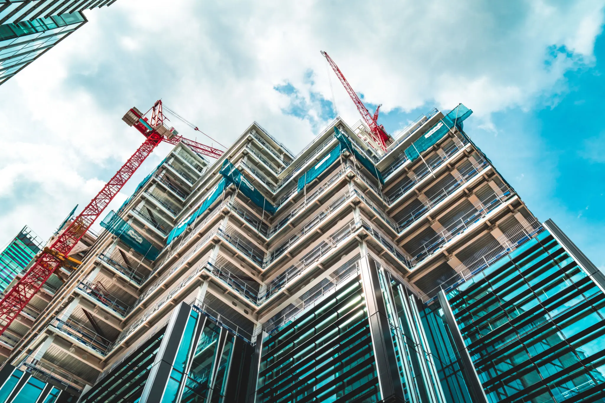 High-rise building under construction with cranes against a blue sky.