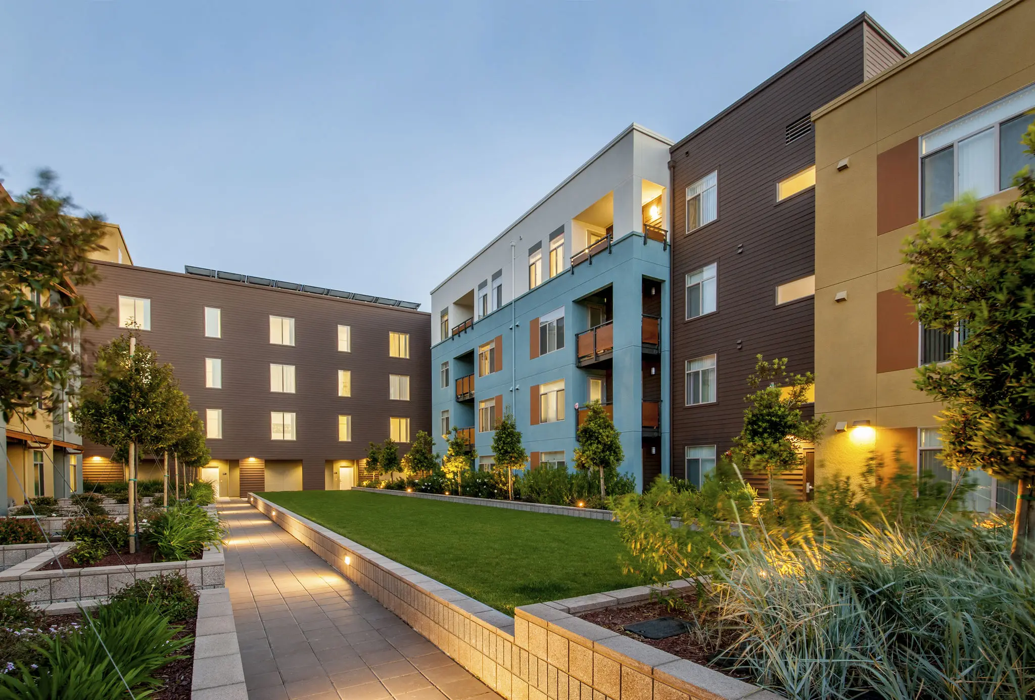 Modern apartment complex with landscaped walkways at dusk.