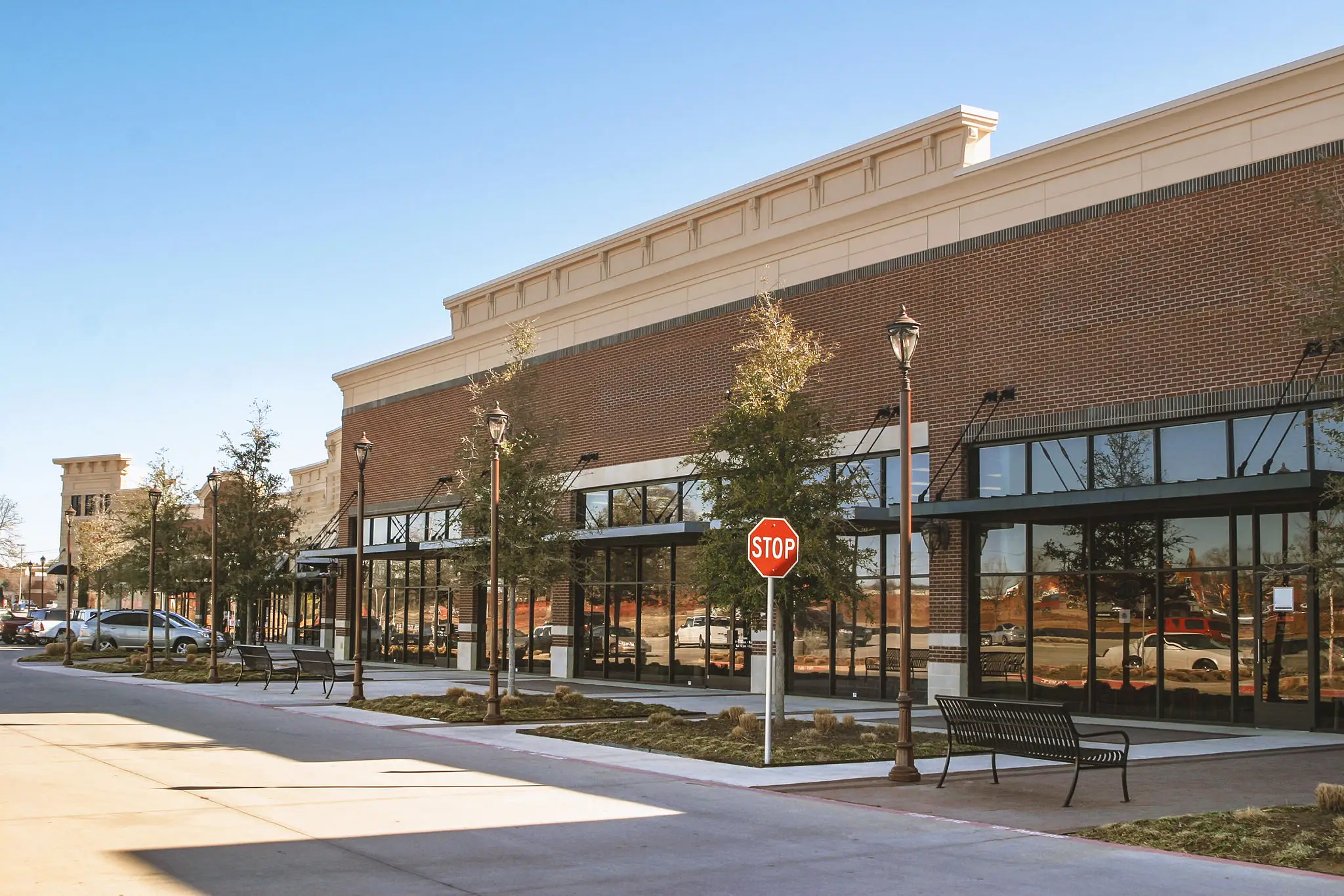 A sunny street view of a modern brick shopping center with large glass windows.