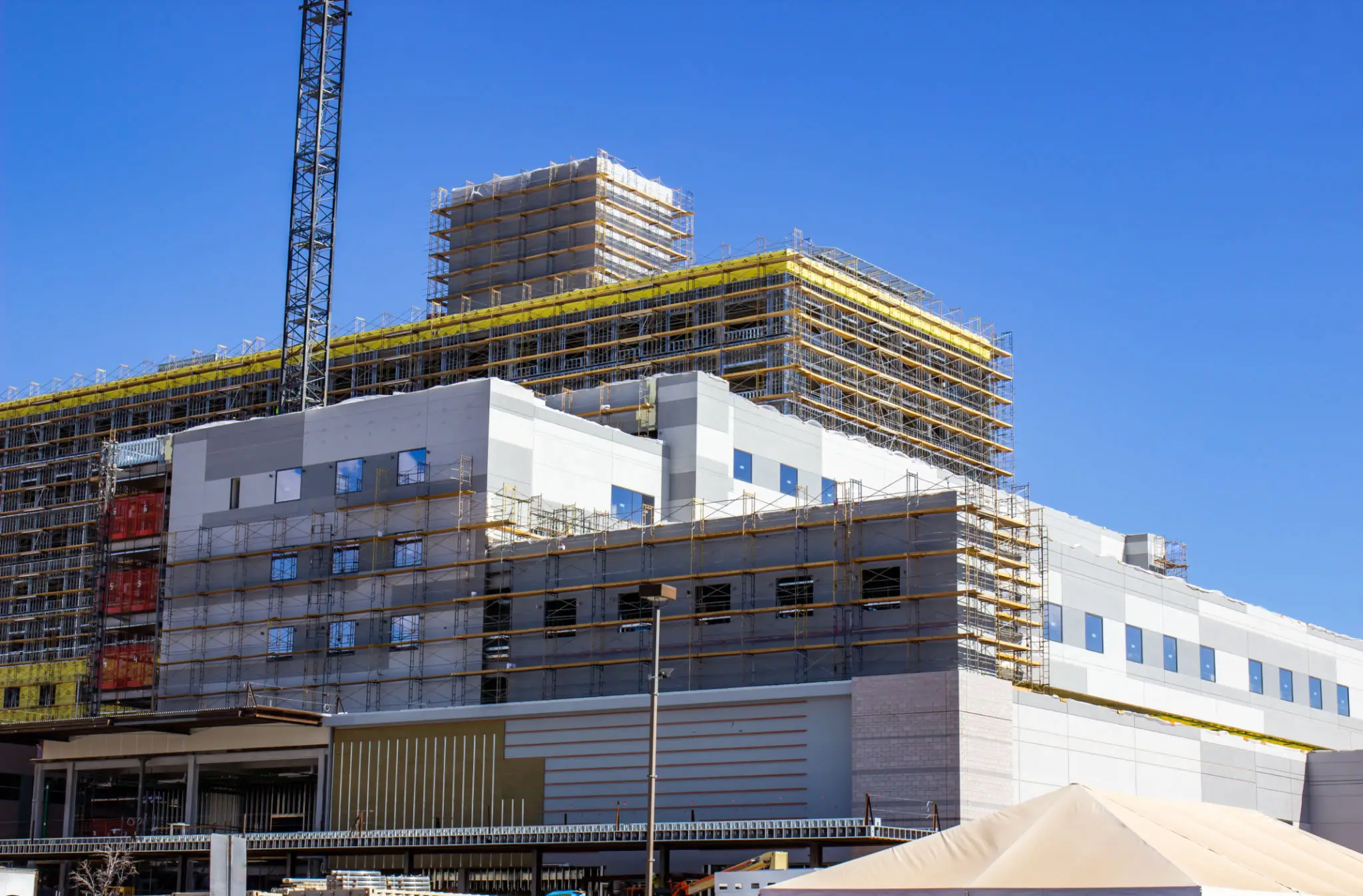 A building under construction with scaffolding and a crane.