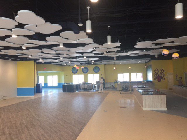 An empty, spacious room with modern ceiling lights and wooden flooring.
