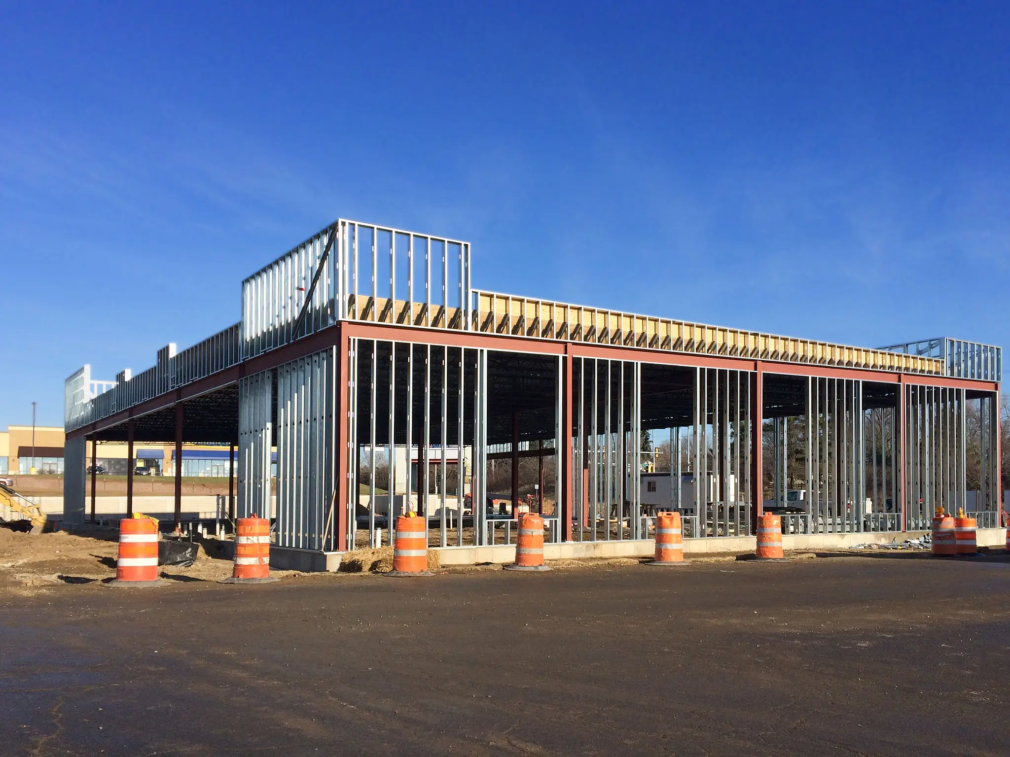 Modern building under construction with steel framework and clear blue sky.
