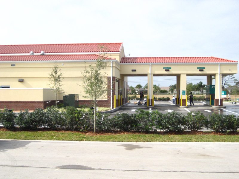 Exterior view of a car wash facility with multiple lanes and landscaping.