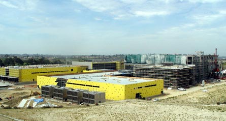 Industrial complex with large yellow buildings under a cloudy sky.