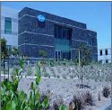 Modern building with stone facade and desert landscaping under clear sky.