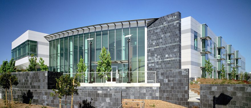 Modern glass building with stone facade under clear blue sky.