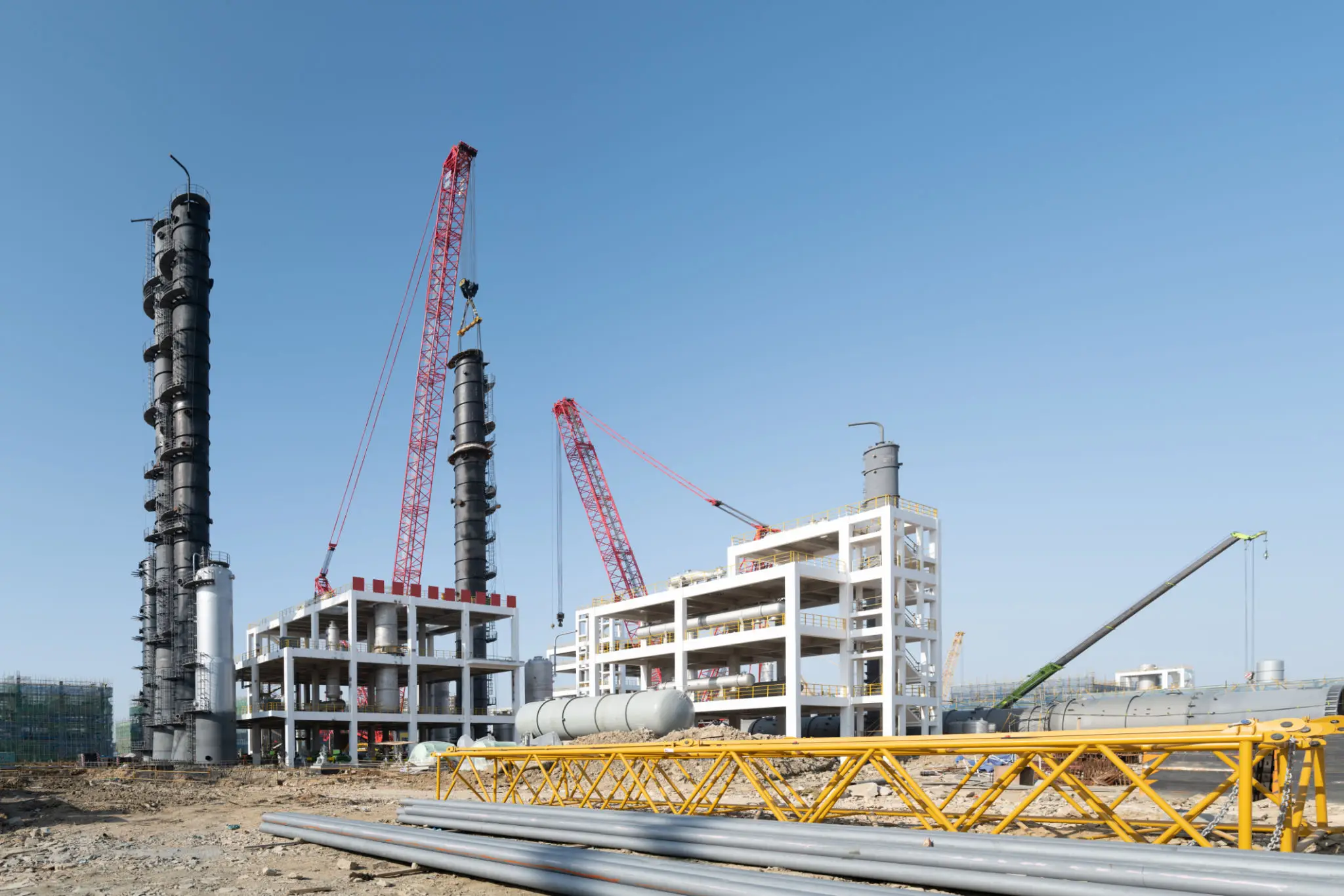 Construction site with cranes and building framework under a clear sky.