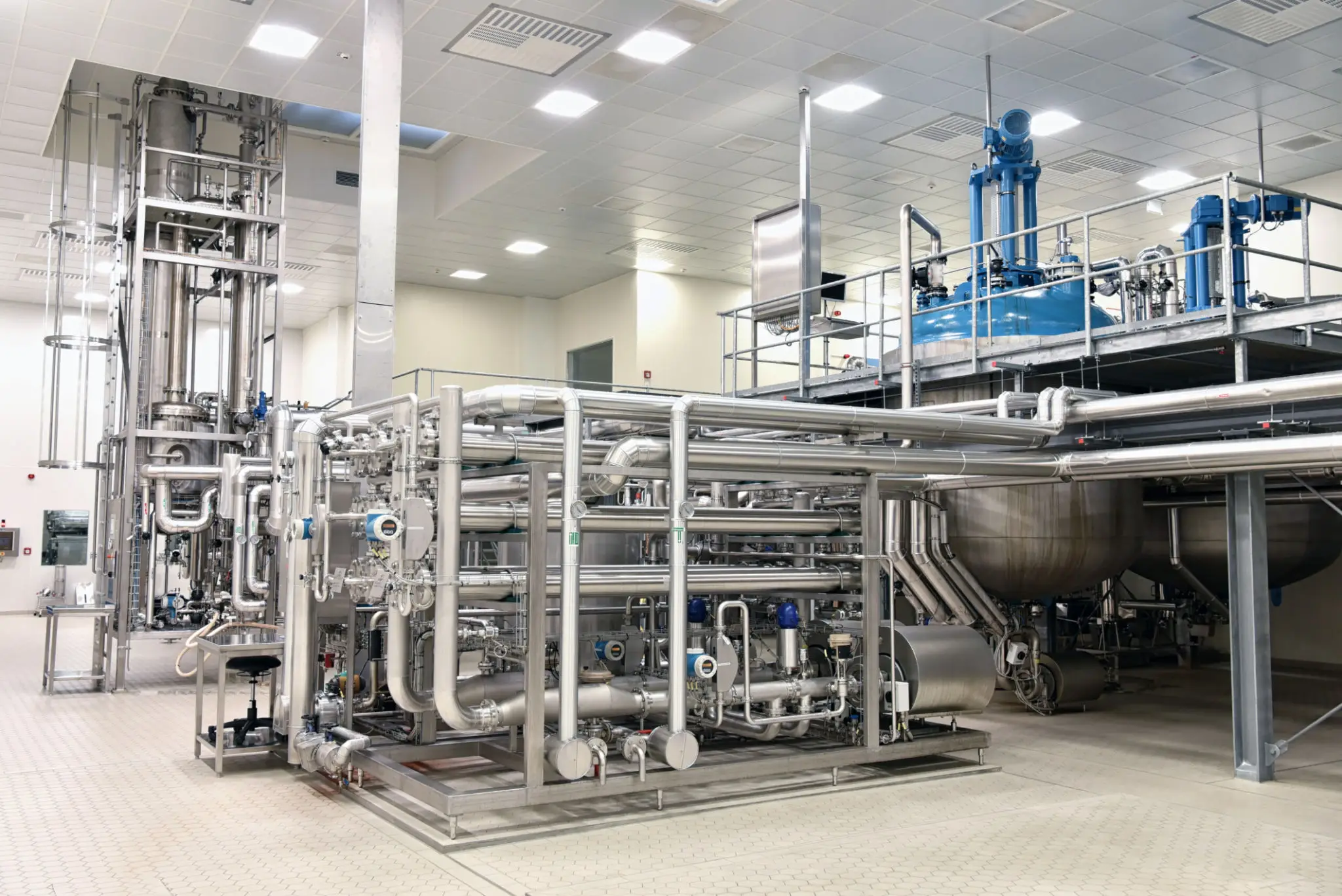 Industrial stainless steel piping and machinery in a clean factory.