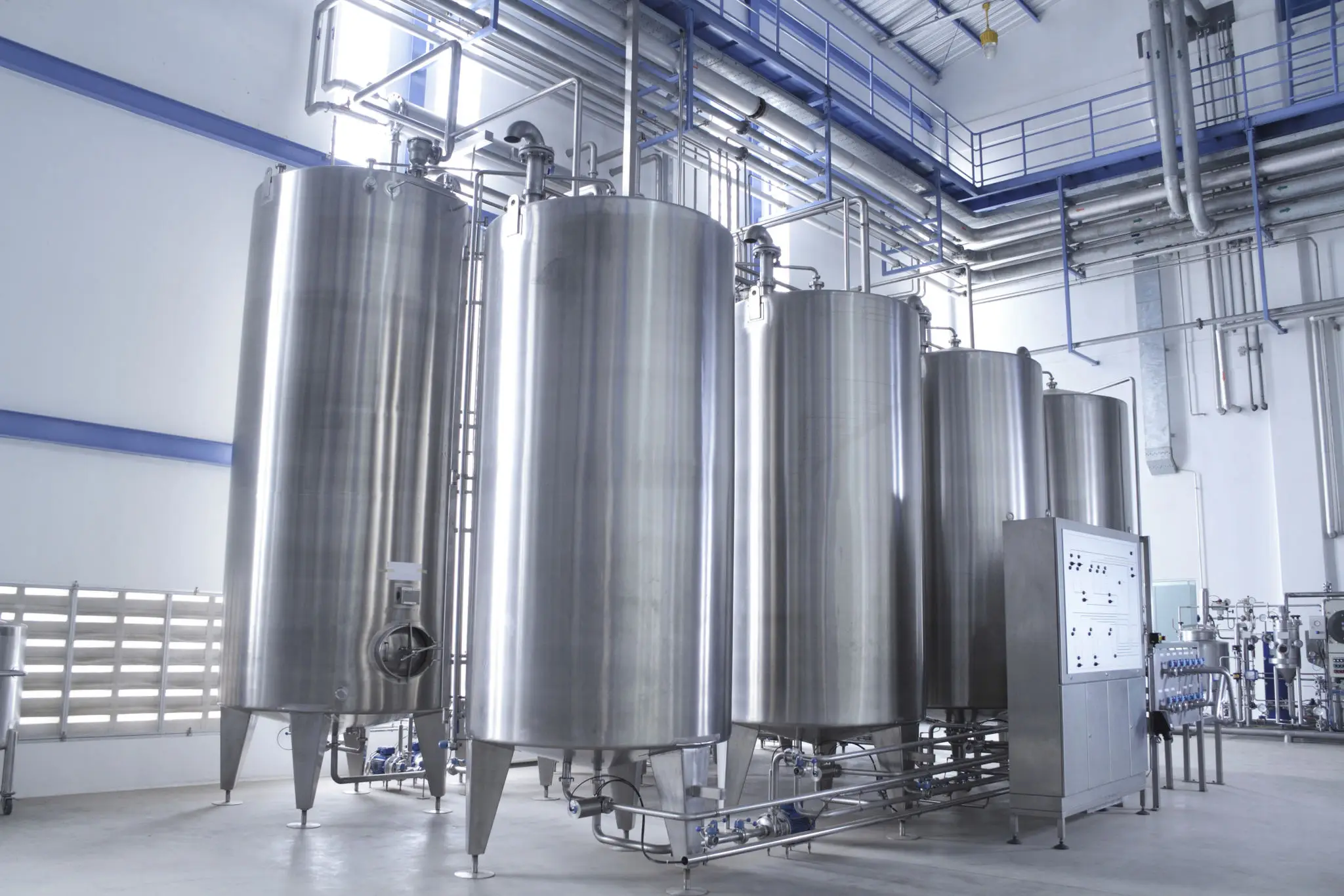 Large stainless steel industrial tanks in a factory setting.
