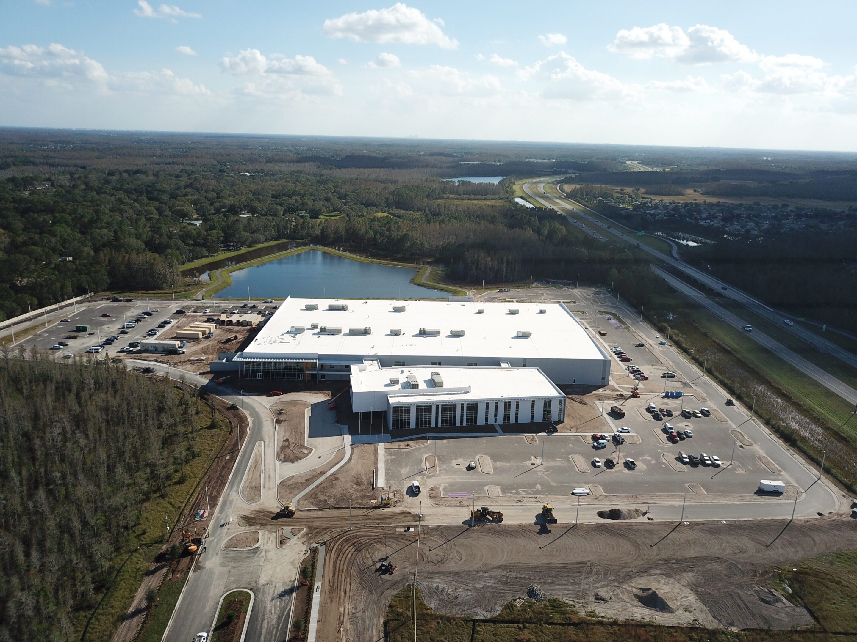 A large warehouse with trucks parked outside under a partly cloudy sky.