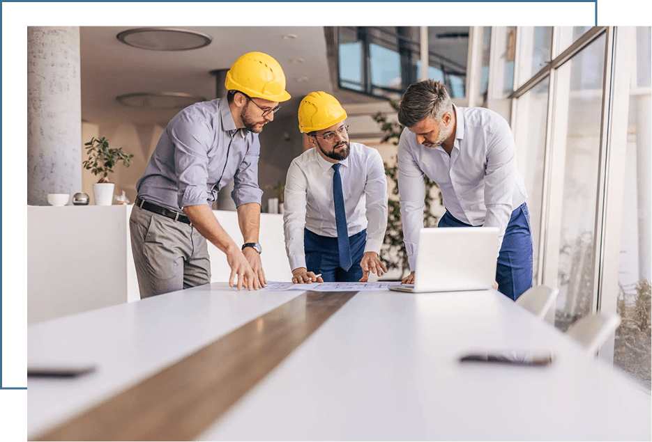 Three professionals discussing a project at a table with blueprints.