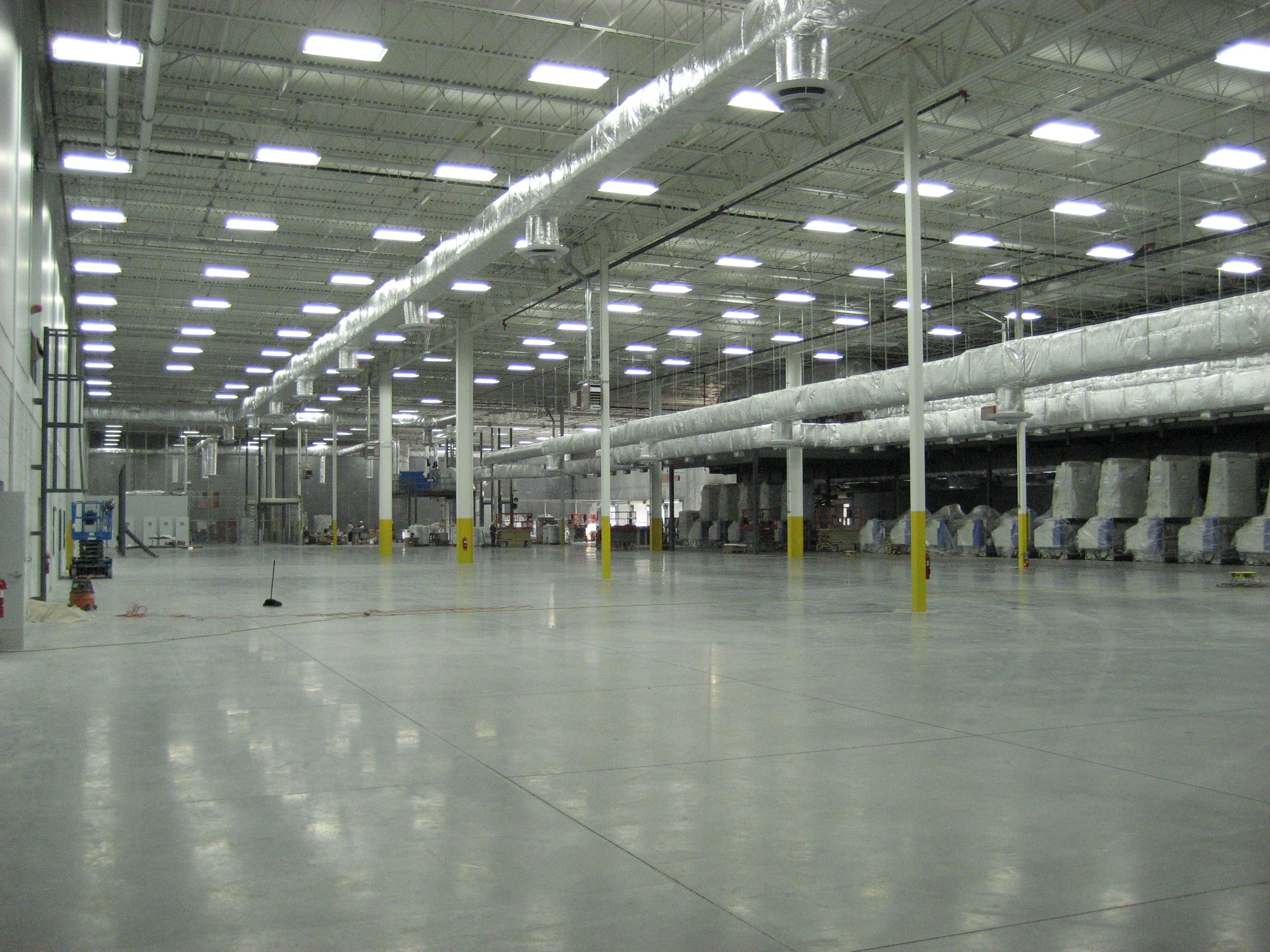 Spacious empty warehouse with high ceilings and bright lighting.